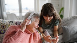 Bestemor og barnebarn ser på mobiltelefon sammen