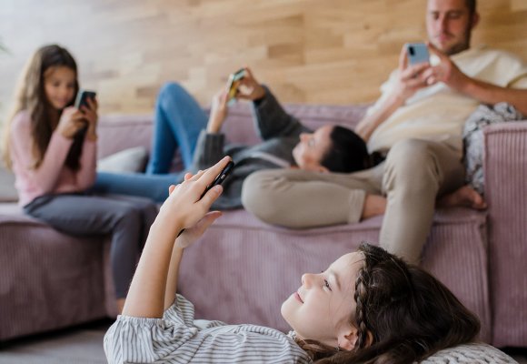 Familie sitter i stua og aller ser på mobiltelefonene sine