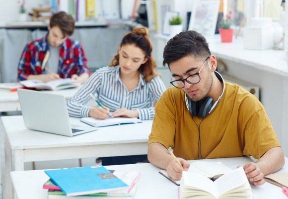 Studenter som sitter å jobber med skoleoppgaver.