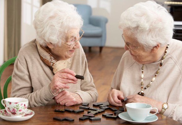 To eldre damer som spiller domino.