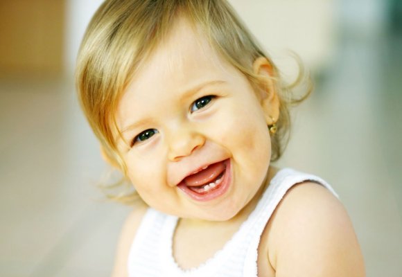 Smilende lite barn som har fått tre tenner nede